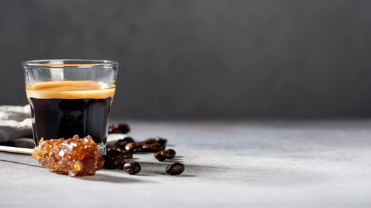 Klarer Kaffeeschnaps in einem Glas, serviert mit gerösteten Kaffeebohnen auf ruhigem Hintergrund